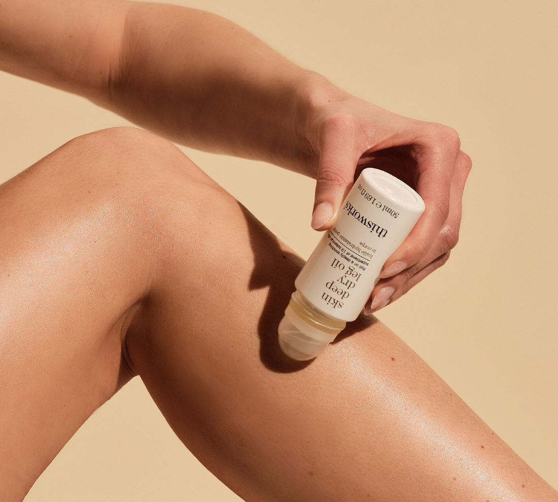 A person applying skin deep dry leg oil on their leg using a rollerball
